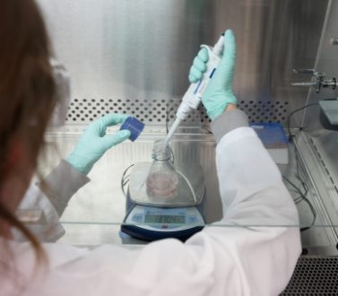 A scientist weighing liquid in a lab.